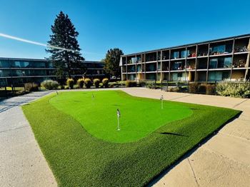 A small putting green in front of a building.